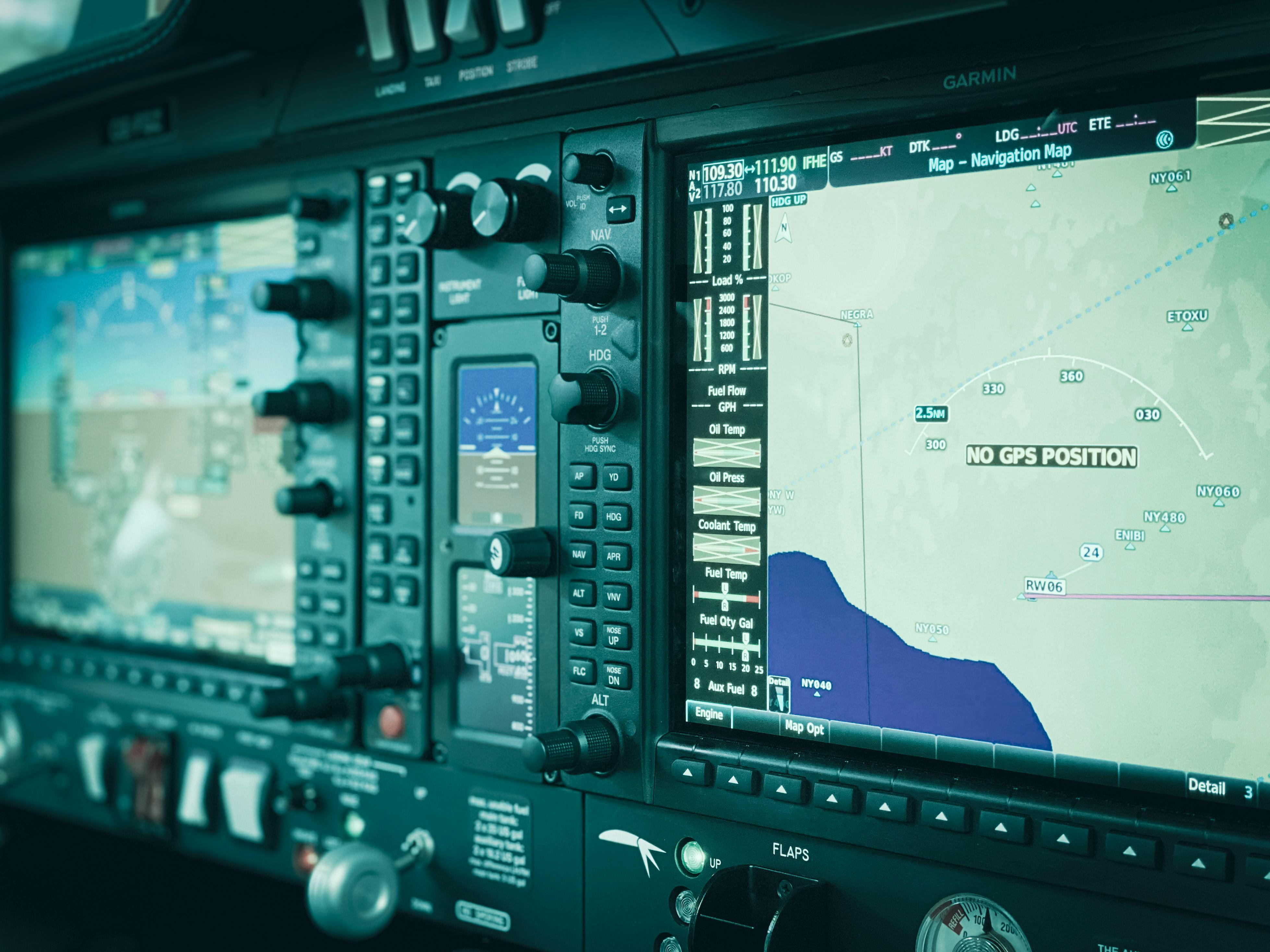Close up of an aviation instrument panel showing two screens with maps and various knobs and buttons.