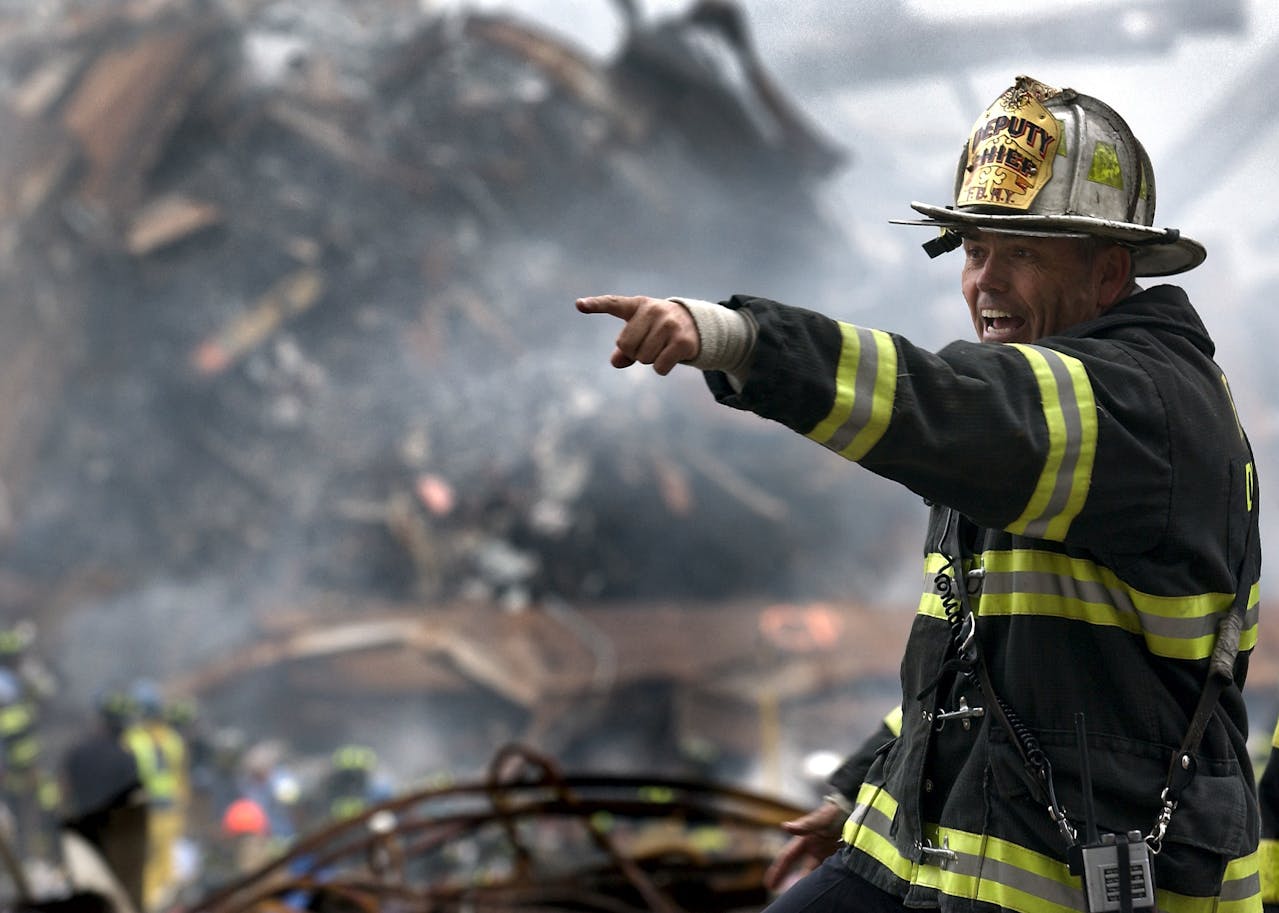Fire Chief directing response at scene surrounded by rubble and smoke.